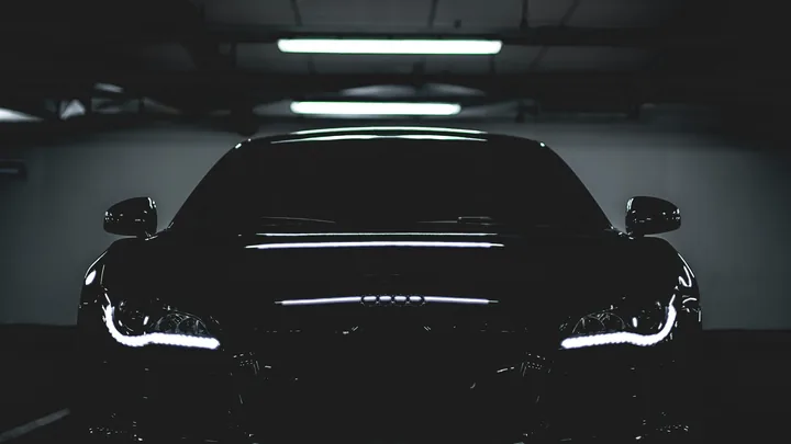 The standard hero photograph: a black car under garage lighting